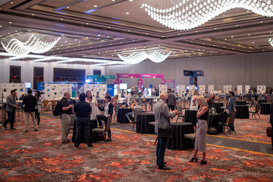 Many people are attending a conference at the Marriott Marquis Houston with many tables and booths.