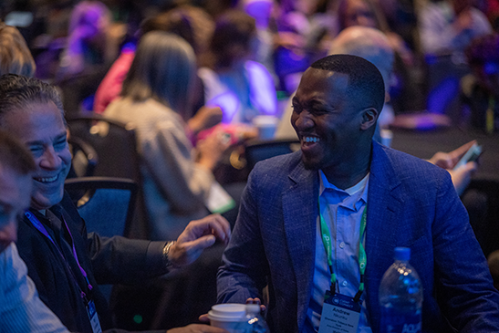 Smiling man at an event with a badge that says Andrew in a crowd of other people.