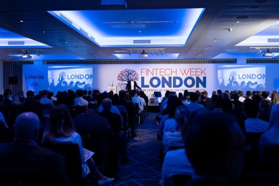 A large audience gathered for the FinTech Week London event at a hotel, illuminated by blue lights.