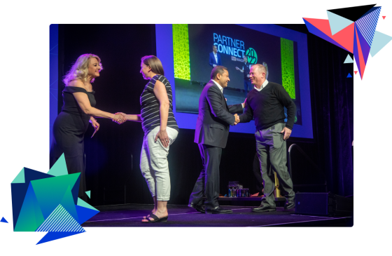 A group of people shake hands on stage at the Partner Connect event in 2023.