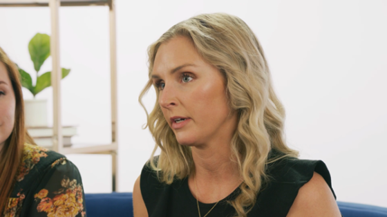 Jorja Smith sits on a blue couch in front of a white wall and speaks to the camera.