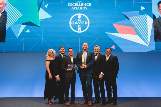 The team of the year awardees standing on stage at the CVENT Excellence Awards, sponsored by Bayer.