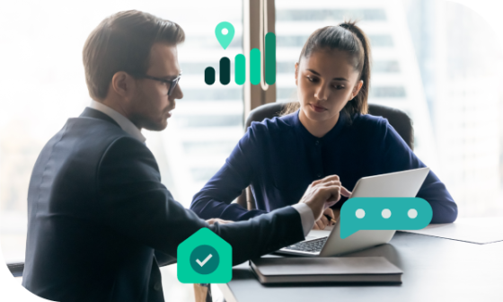 Two people in office are working on laptop with some icons in front of them.