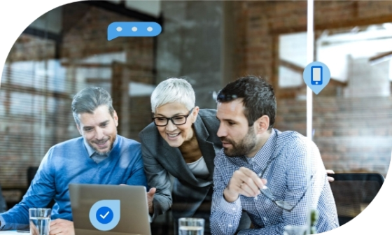 Three professionals sitting around a laptop, smiling and discussing with speech and mobile icons above them.