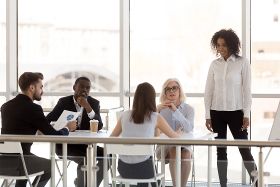 Group of business people having a meeting in a bright office with large windows and a modern design.