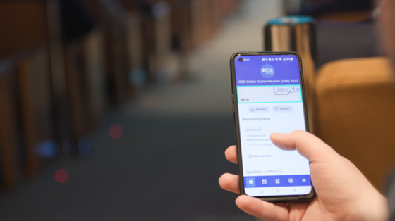 A person holding a phone with Elevate app open showing the happening now screen.