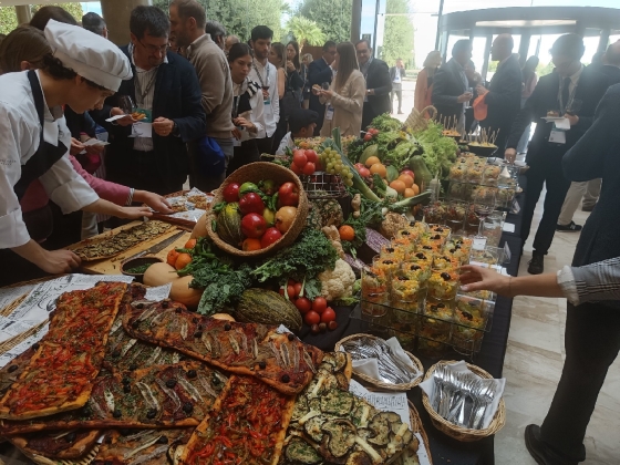 The event's food spread, including fruits, vegetables, and cooked dishes, is displayed on a table.