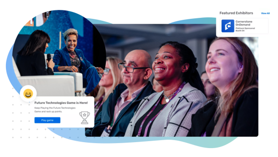 Smiling people at an event with an image of a game pop up on the left.