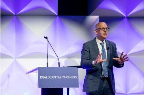 A man in formal wear is speaking in front of a podium with "Dyal Capital Partners" written on it.