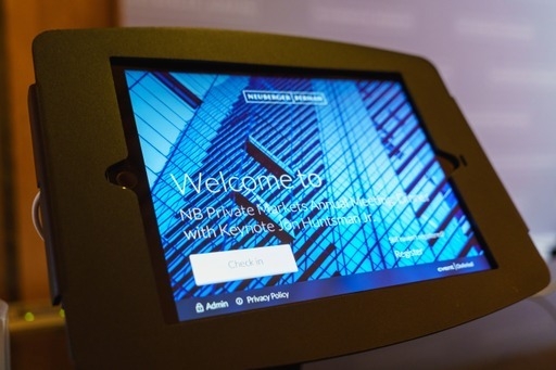 On arrival, a tablet displays the "Welcome to NB Private Markets Annual Meeting" message in blue.