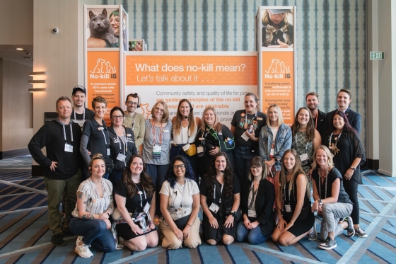 Group of 23 people in front of a sign that says What does no-kill mean? Let's talk about it.