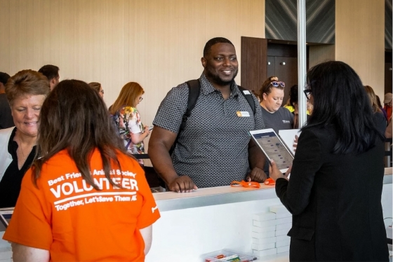 Registration desk with a man in a gray shirt and a woman in an orange shirt.