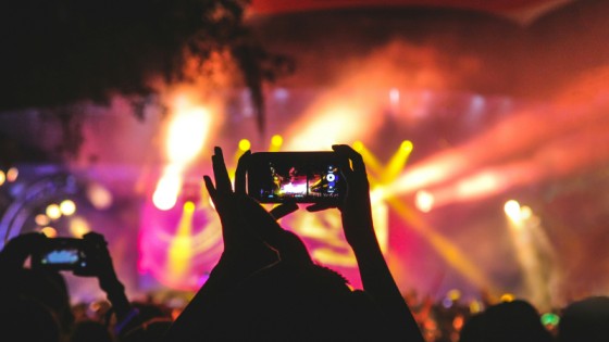 Event stage lighting with a person holding a phone up to record the event.