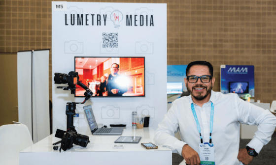 Lumetery media stand with Juan Cancino in front of it at a trade show.