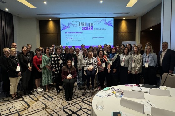 Group of women pose for a photo in front of a projector screen displaying text about empowering success.