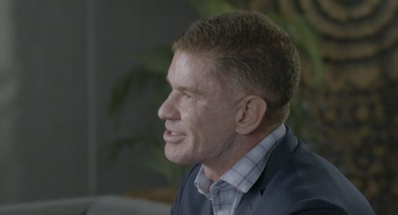 A man in a blue suit is smiling and looking at something in front of him.