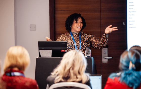 A lady with leopard print dress is giving a presentation to an audience.
