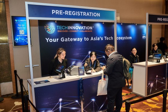 A man at a Tech Innovation pre-registration booth with a "Your Gateway to Asia's Tech" sign.