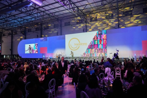 A crowd of people are attending an event with a large screen in the background.