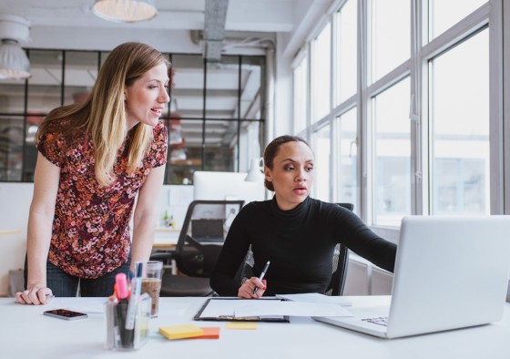 Two women working on a computer with concerned faces