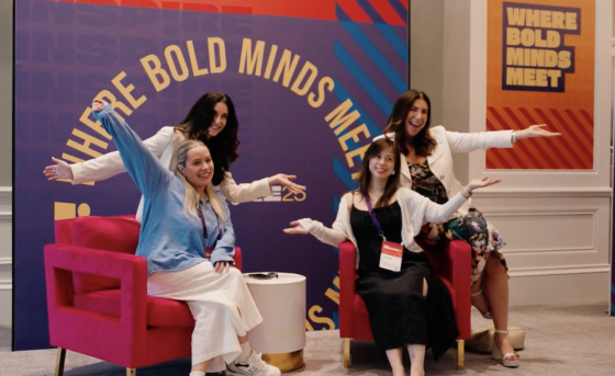 Women smiling and sitting in a chair for a photo at Docebo Inspire
