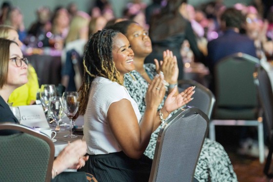 Two women at awards gala clapping and smiling 