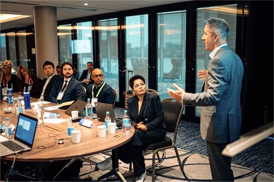 Meeting in a formal setting with a room full of meeting members 