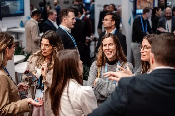 Colleagues chat and laugh holding drinks at a conference networking event.