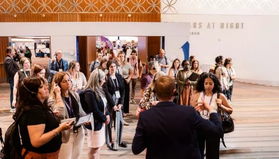 Large group of conference attendees wearing audio headsets follows a guide during a walking tour.