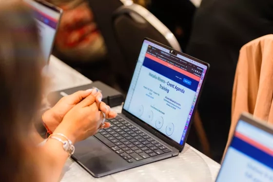 Close-up of hands typing on a laptop keyboard displaying a Cvent event agenda training page.