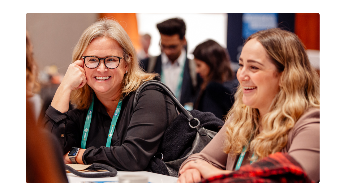 Two women laughing in conversation at a conference