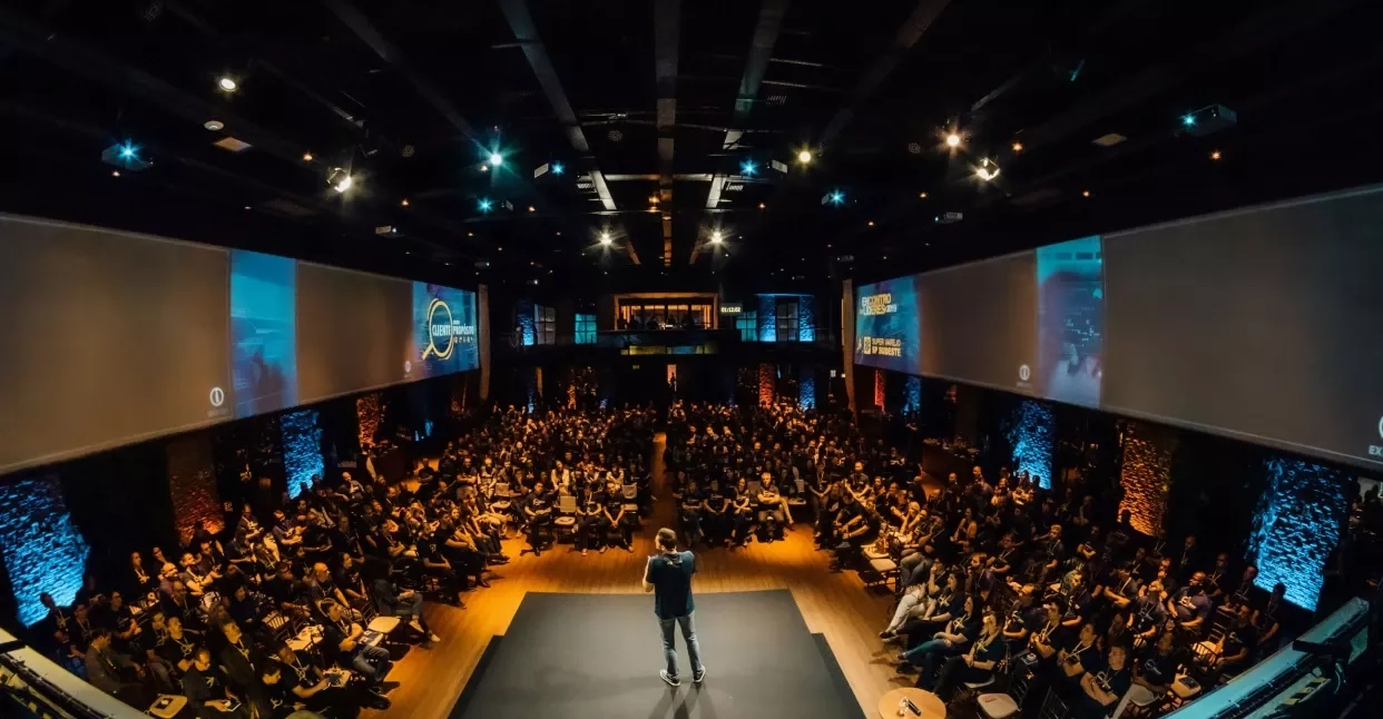 A speaker on stage with crowd in the event space