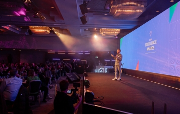 Host presenting on stage in front of a crowd at the Cvent Excellence Awards in London.