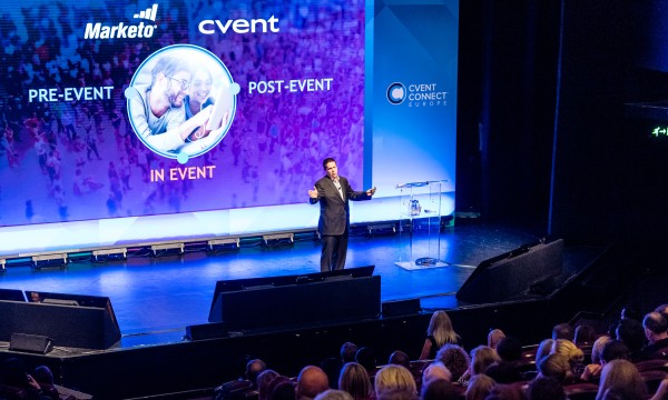Man on stage with a large screen behind him, showing a presentation about events.