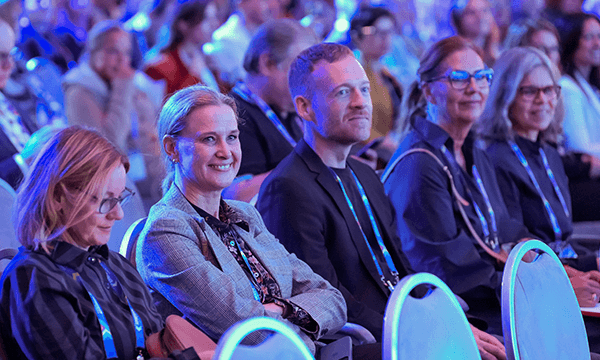Group of attendees sit in chairs at a meeting with blue light.
